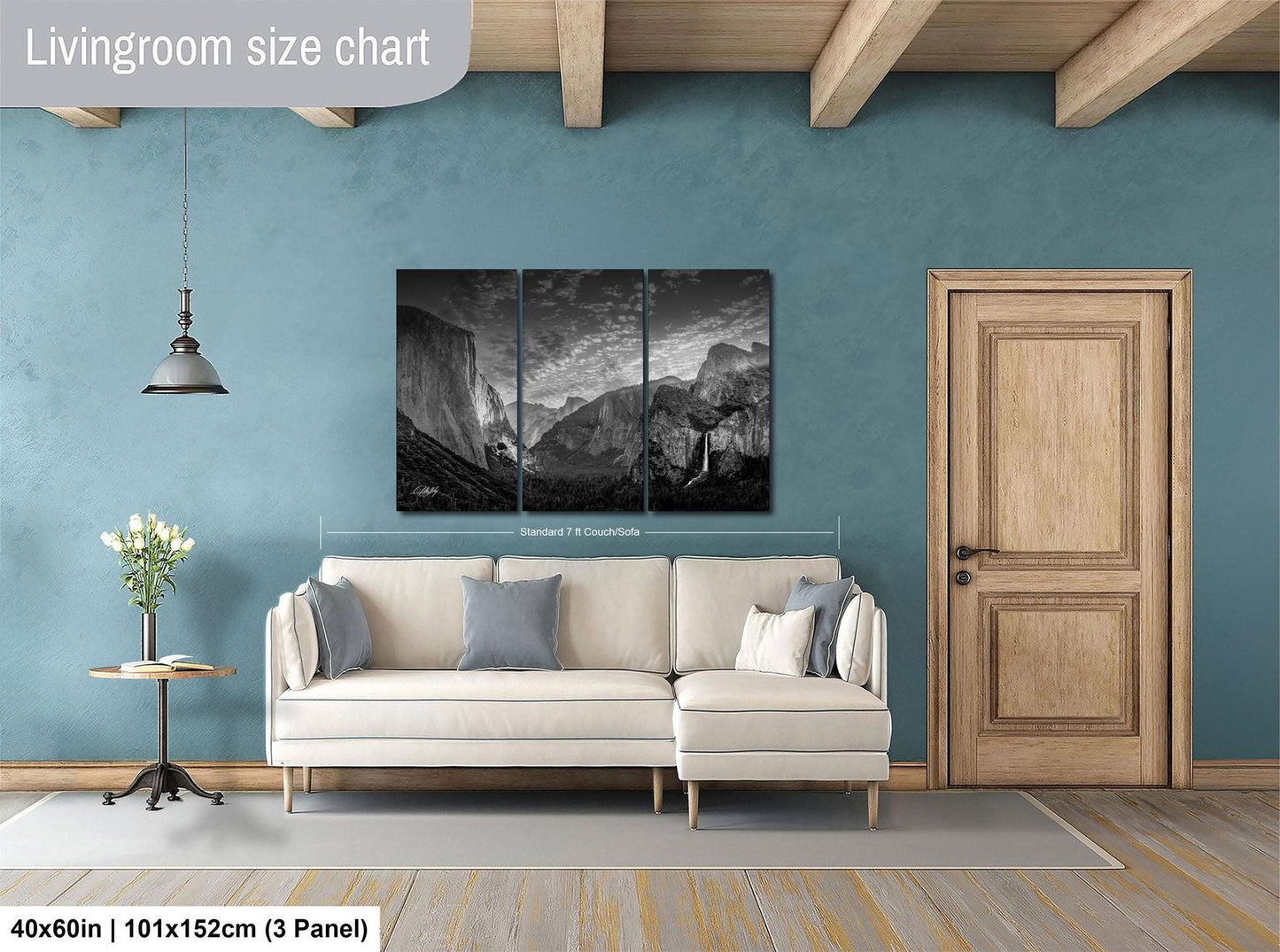 The image is a living room with a large, three-panel landscape painting hanging on the wall. The painting depicts a mountainous scene, and the room has a white sofa and a wooden door.