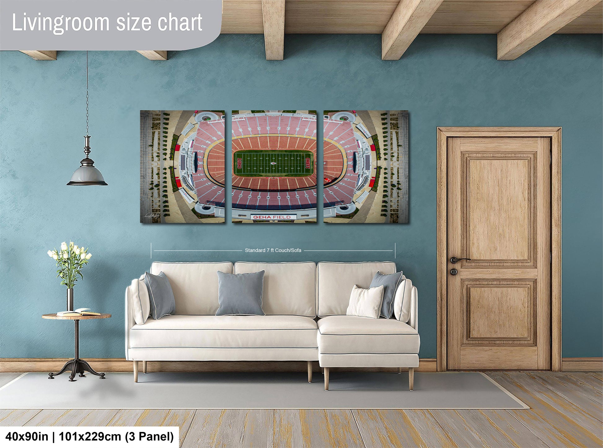 The image is a living room with a large wall-mounted 3D painting depicting a football stadium. The painting is framed and hangs above a white sofa, which is positioned in front of a wooden door. The room has a wooden floor and a small table with a vase of flowers. The wall is painted in a light blue color, and the overall layout and design of the room suggest a modern and stylish interior.