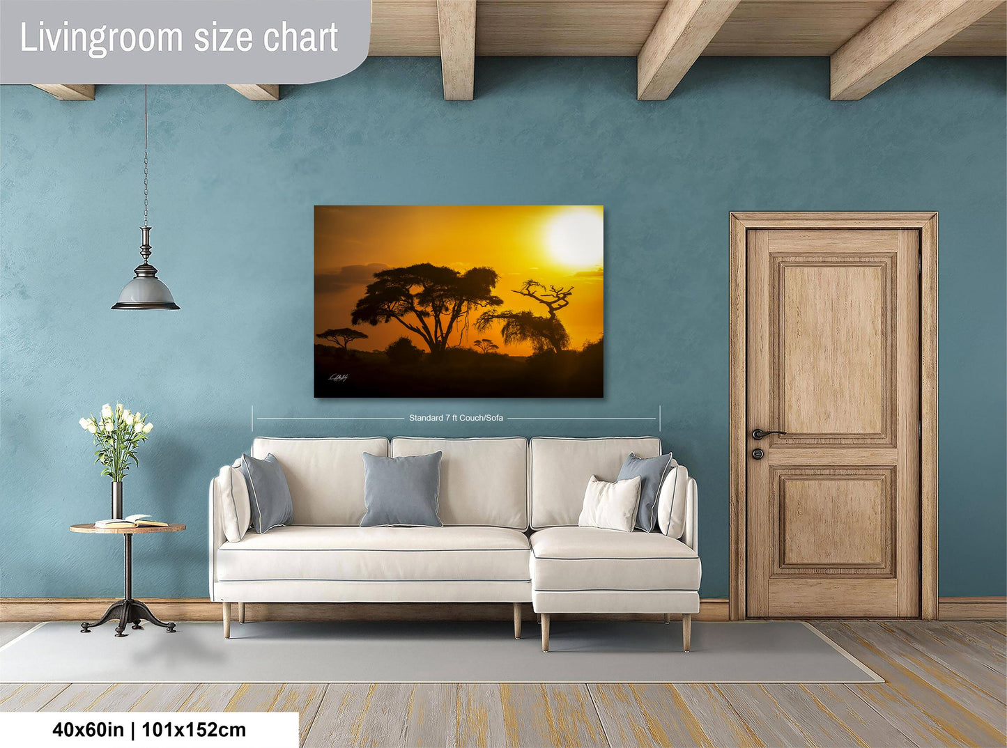 a living room with a large painting of a sunset landscape hanging on the wall. The painting is framed in a white frame and measures 40 inches by 101.5 centimeters. The room has a white sofa and a wooden door, creating a cozy and inviting atmosphere.