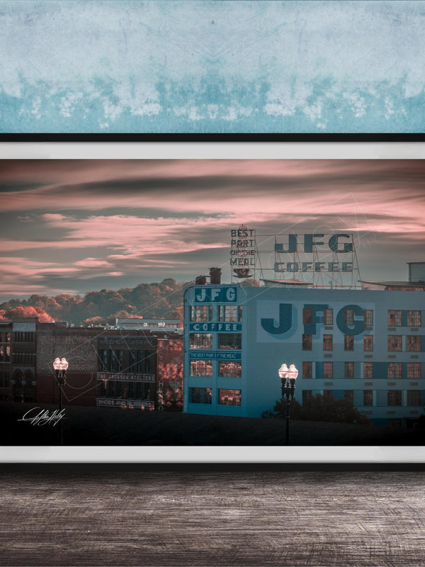 A framed photograph of a cityscape at sunset, with buildings and a sign for JFG Coffee prominently displayed.