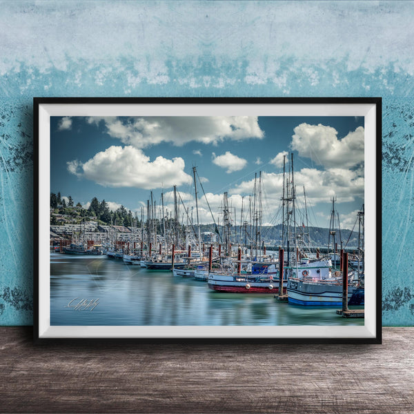 A framed photograph of a harbor with numerous sailboats docked in the water, set against a backdrop of a cloudy sky.