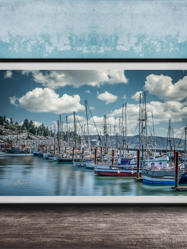 A framed photograph of a harbor with numerous sailboats docked in the water, set against a backdrop of a cloudy sky.