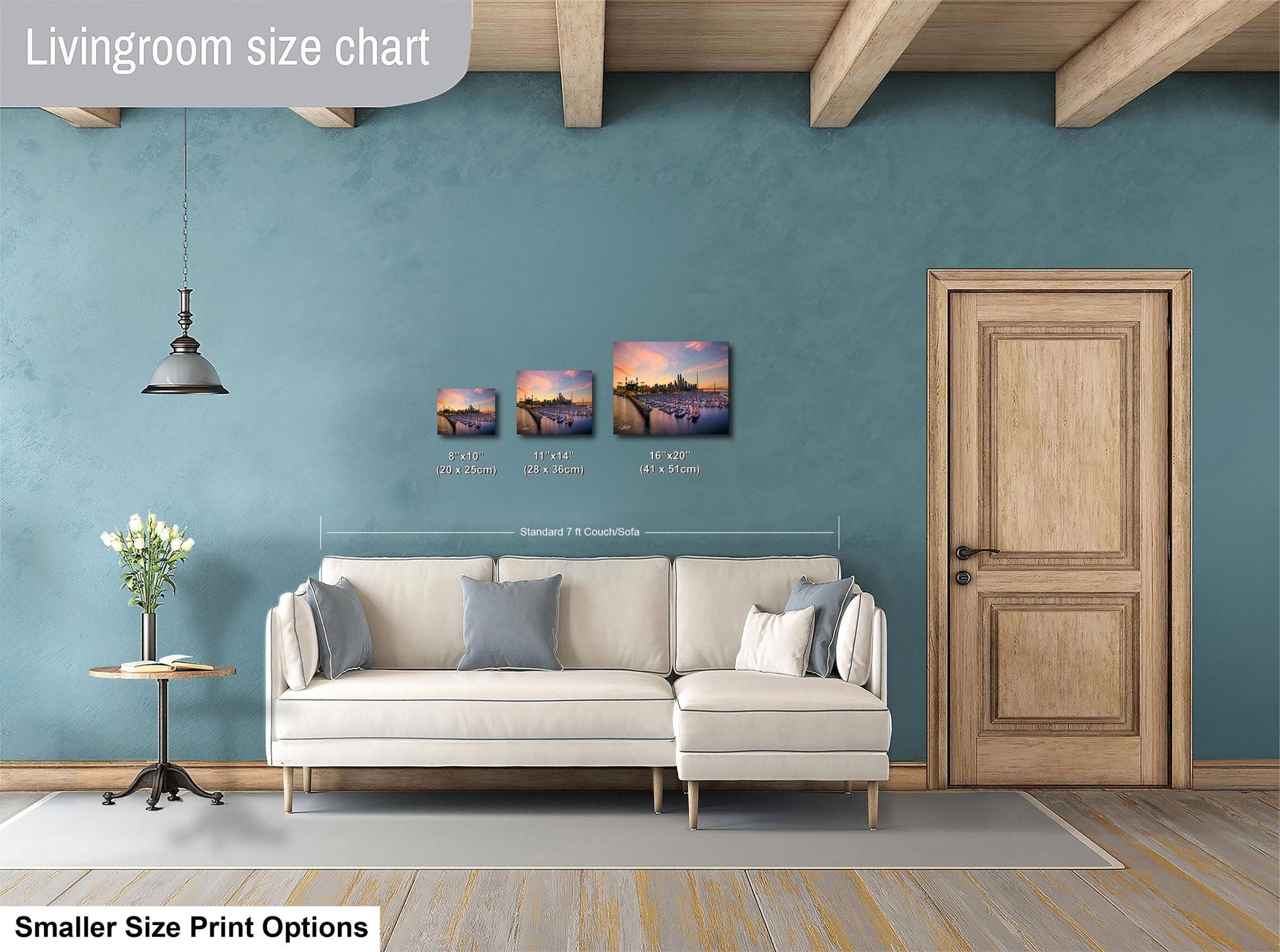 a living room with a white sofa, a wooden door, and a hanging light fixture. There are three framed pictures of landscapes displayed on the wall above the sofa.