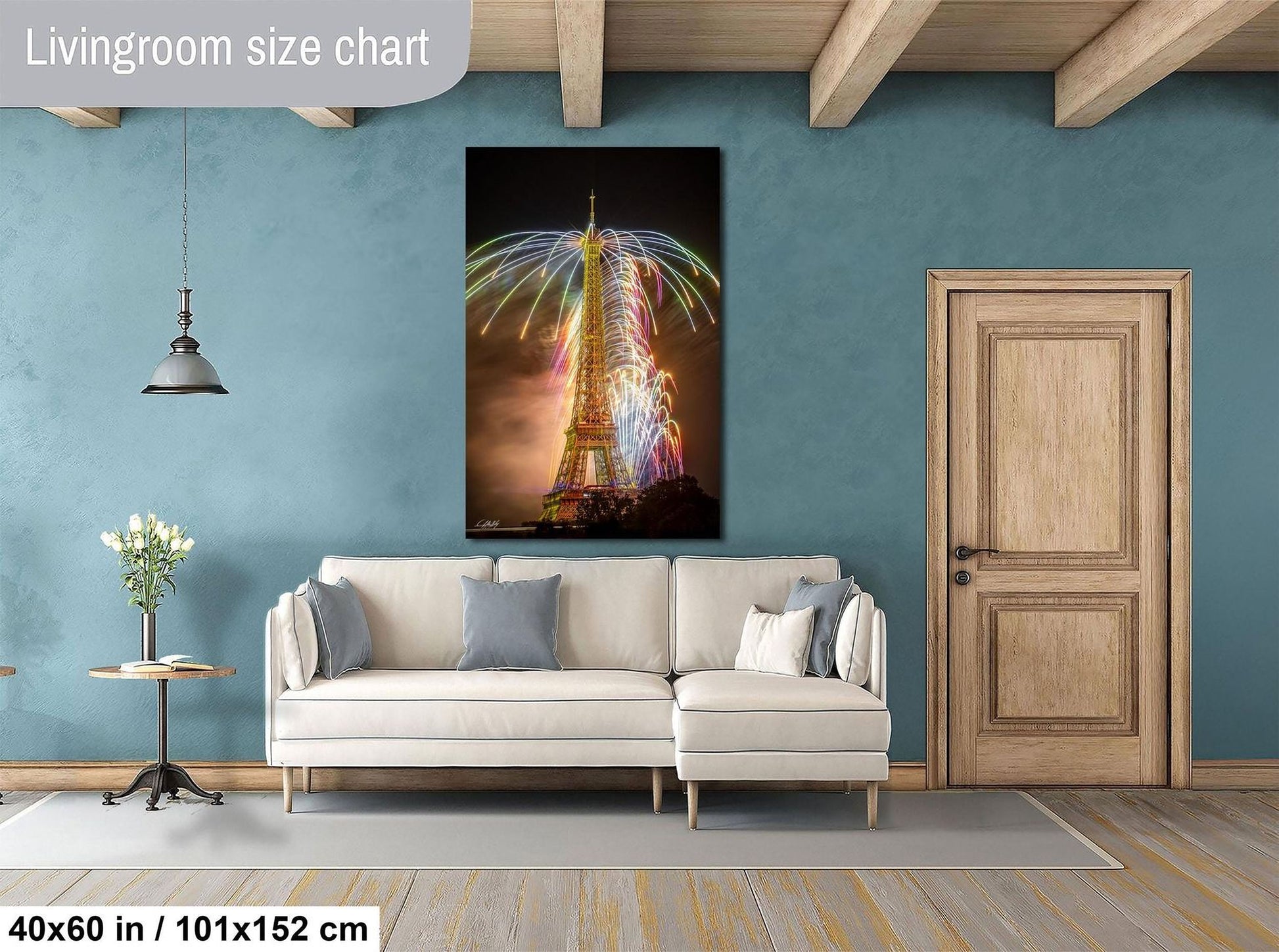 a living room with a large white sofa, a wooden door, and a framed picture of the Eiffel Tower with colorful lights.