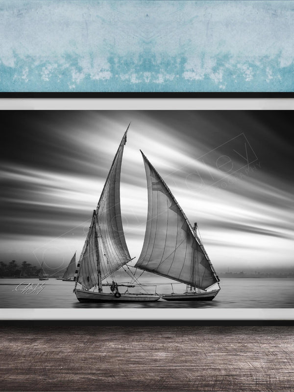 This luxury black and white fine art photograph captures a felucca sail boat drifting along the Nile River at sunset near Luxor, Egypt. Soft fog and minimalist composition create a timeless, monochrome aesthetic rooted in Egyptian river culture. Ideal for collectors and interior designers seeking refined, museum-quality wall art that embodies elegance, simplicity, and enduring calm. black white nile river art, felucca sailboat wall decor, luxor egypt monochrome print, luxury minimalist wall art
