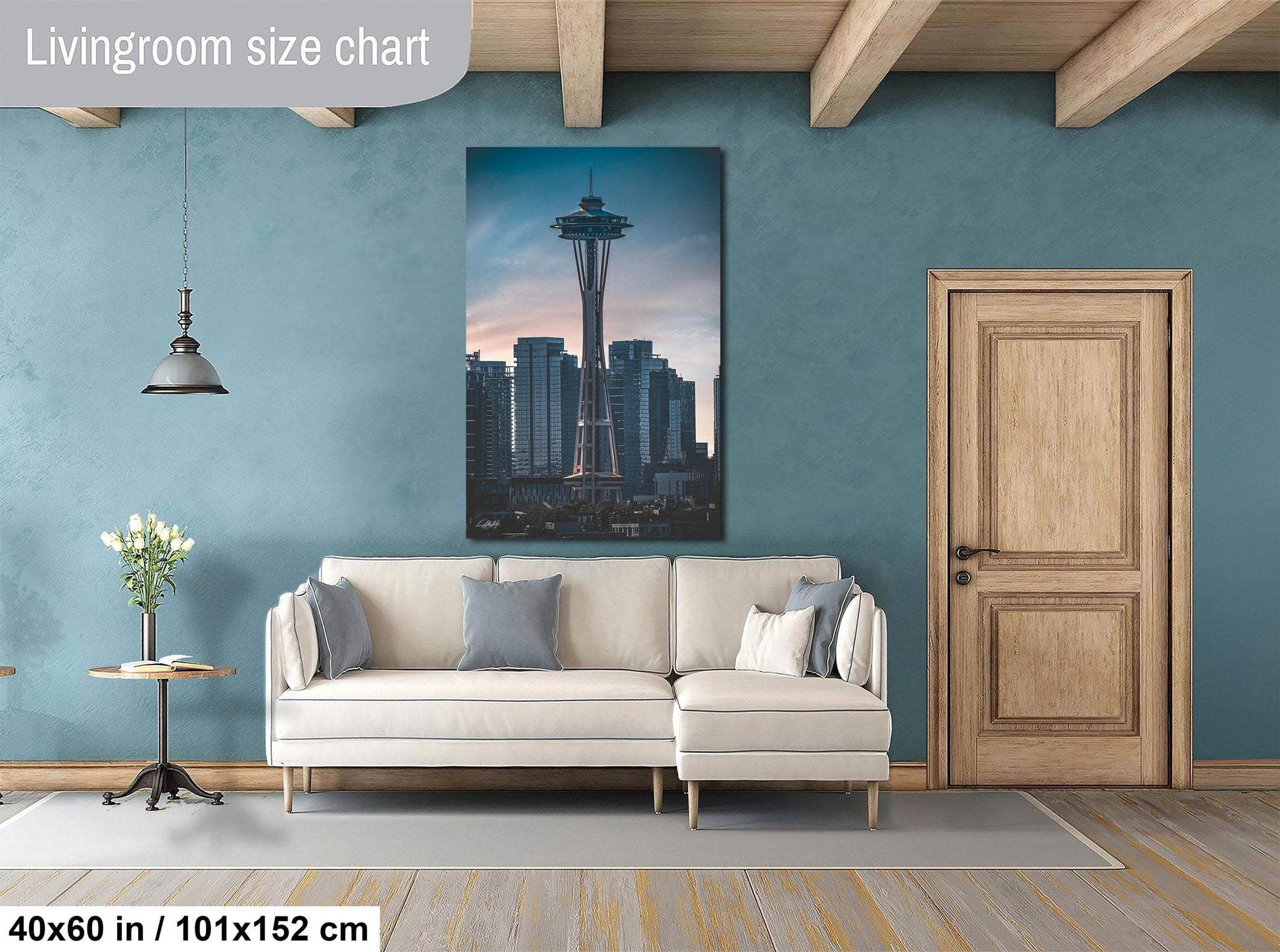 a living room with a large white sofa, a wooden door, and a painting of the Space Needle on the wall.