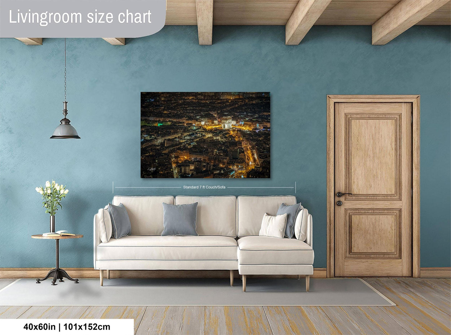 a living room with a large cityscape painting hanging on the wall. The painting is approximately 40 inches wide and 115 centimeters tall. The room has a white sofa, a wooden door, and a small table with a vase of flowers.