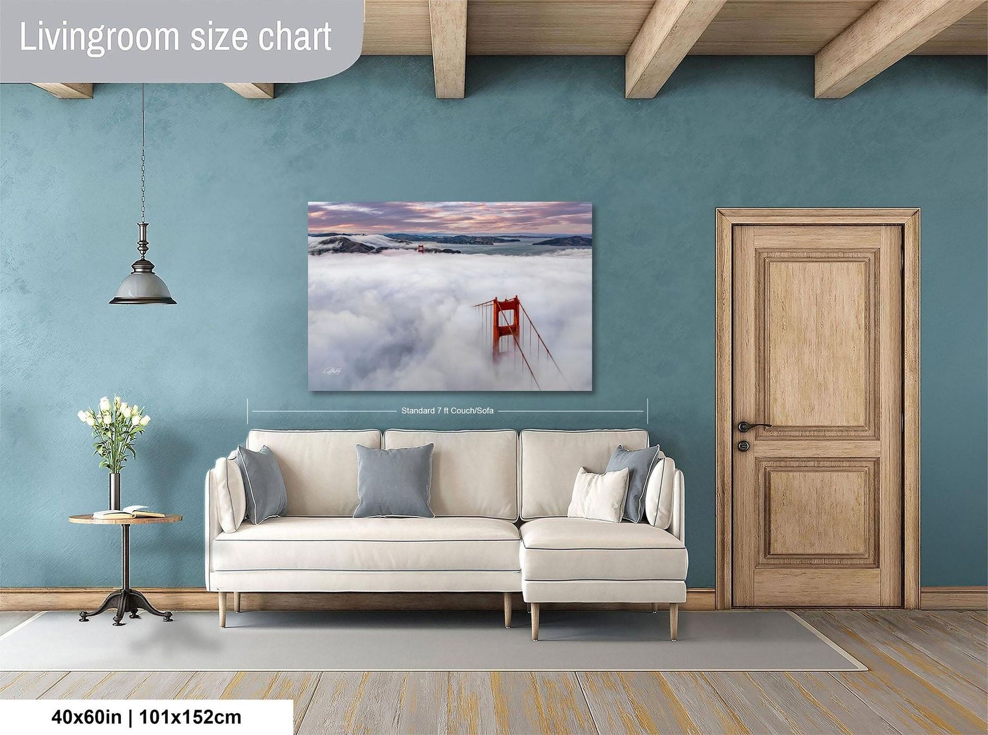 a living room with a large painting of a bridge in the clouds hanging on the wall. The painting is framed and measures 40 inches by 101.5 centimeters. The room has a white sofa, a wooden door, and a small table with a vase of flowers.