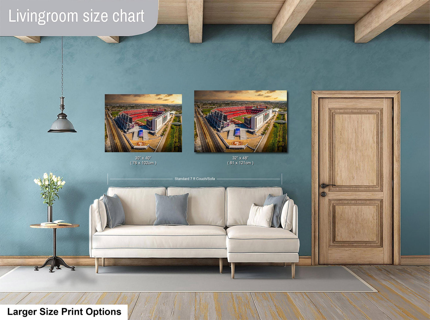 a living room with a white sofa and a wooden door. Above the sofa, there are two framed pictures of a cityscape, and the wall has a blue color. The living room appears to be well-lit and decorated.