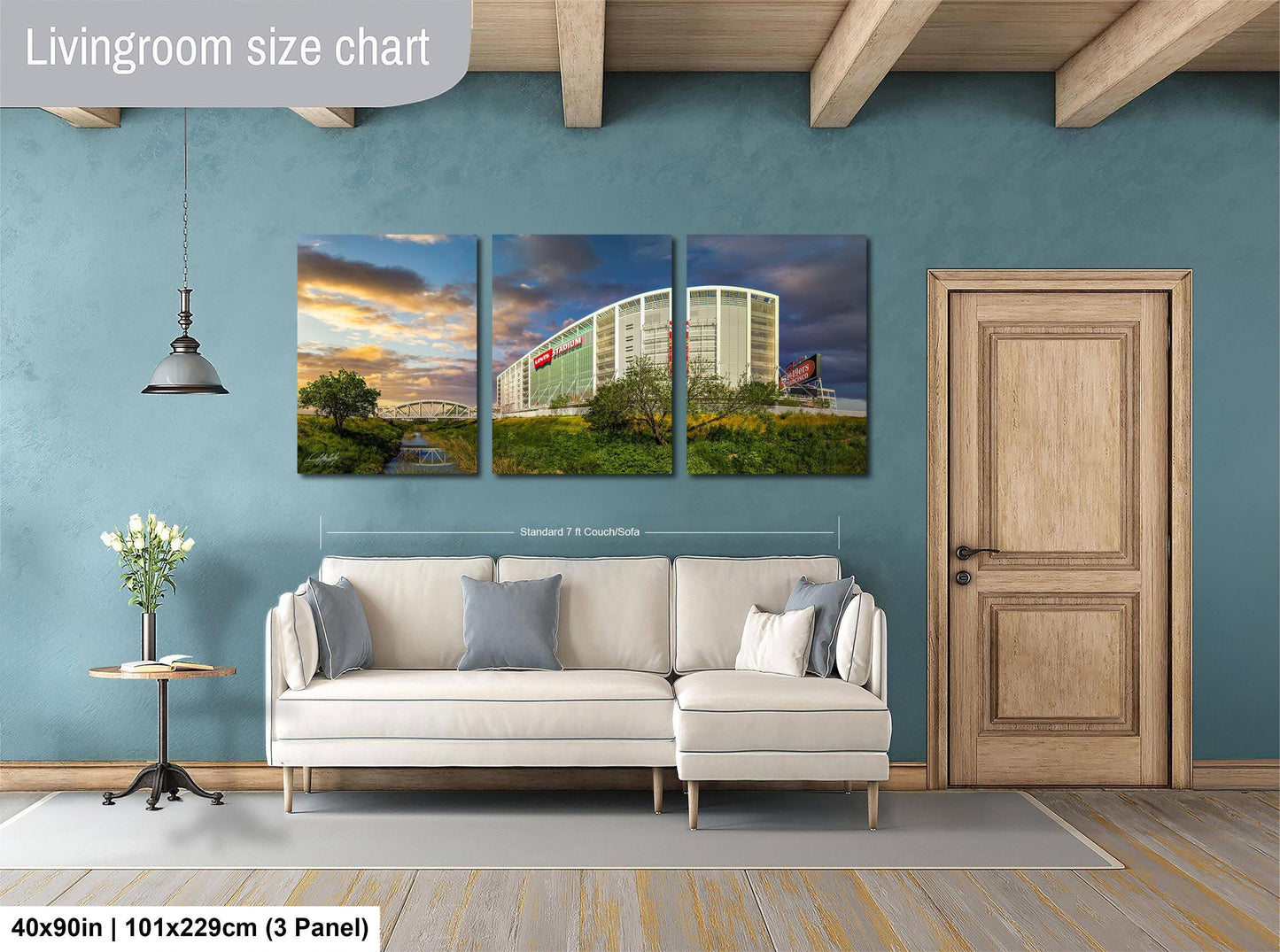 The image is a living room with a white sofa and a wooden door. Above the sofa, there is a large wall art collage depicting a building and a scenic landscape. The wall art is framed by a wooden border and is approximately 40 inches wide and 101.29 cm in height.