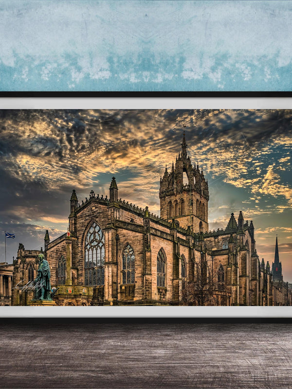 A framed photograph of a large, ornate cathedral with a castle-like structure, set against a dramatic sky with clouds and a sunset.
