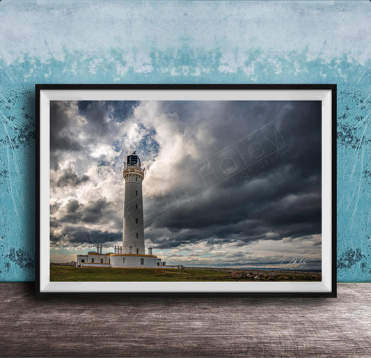 A framed photograph of a lighthouse against a stormy sky, with the lighthouse standing tall on a grassy field.
