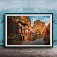 a large, ancient stone structure carved into a cliff face, with a river flowing through the carved grooves.