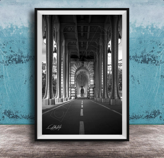 A black and white photograph of a long, narrow hallway with tall columns and arches, leading to a doorway at the end. The hallway appears to be part of a larger architectural structure, possibly a building or a church.