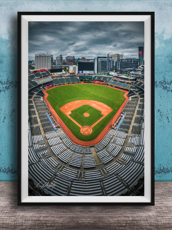 A framed photograph of a baseball stadium with a city skyline in the background.