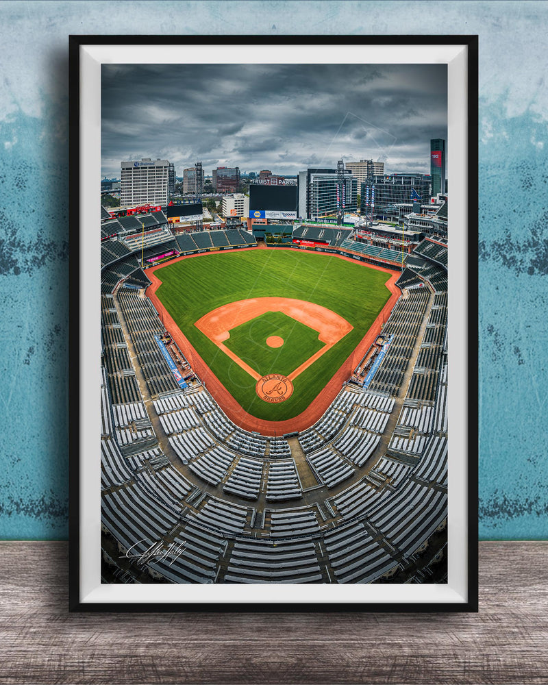 A framed photograph of a baseball stadium with a city skyline in the background.