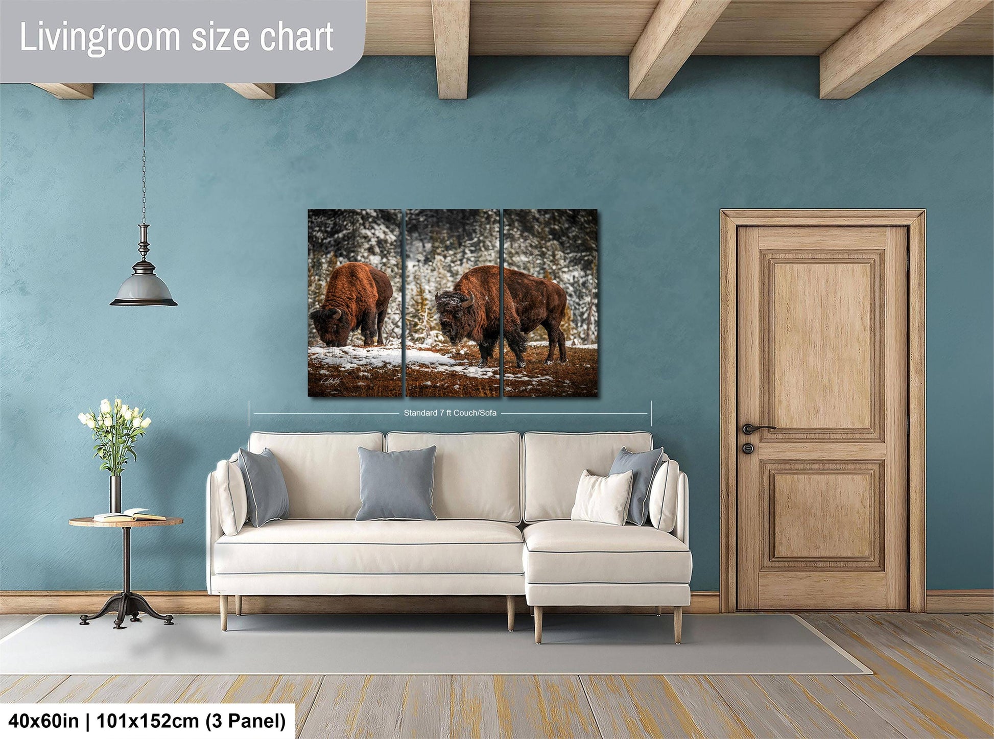 The image is a living room with a large painting of two bison in a snowy forest hanging on the wall. The painting is divided into three panels, and the living room has a white sofa and a wooden door.