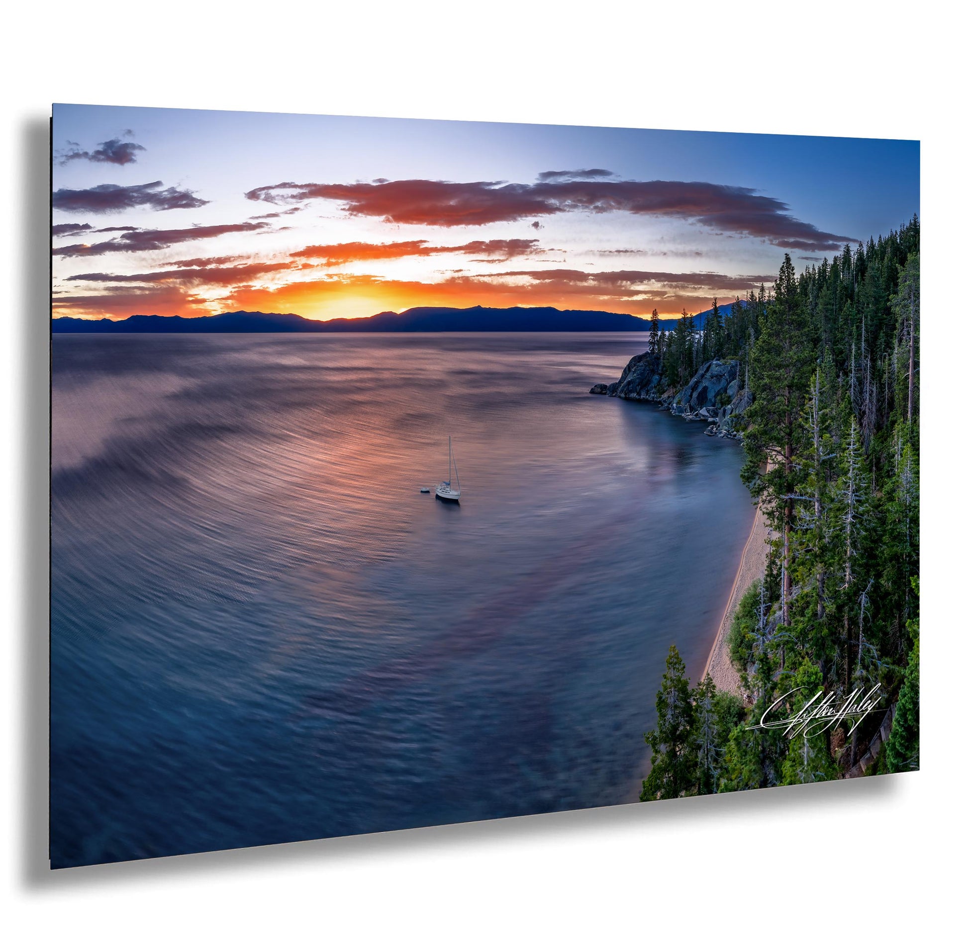 a serene lake at sunset, with a small sailboat gently floating on the calm waters. The sky is filled with vibrant hues of orange and pink, creating a stunning backdrop for the tranquil scene. The lake is surrounded by lush green trees and rocky cliffs, adding to the picturesque landscape. The image is a captivating representation of nature's beauty and the peacefulness of the moment.