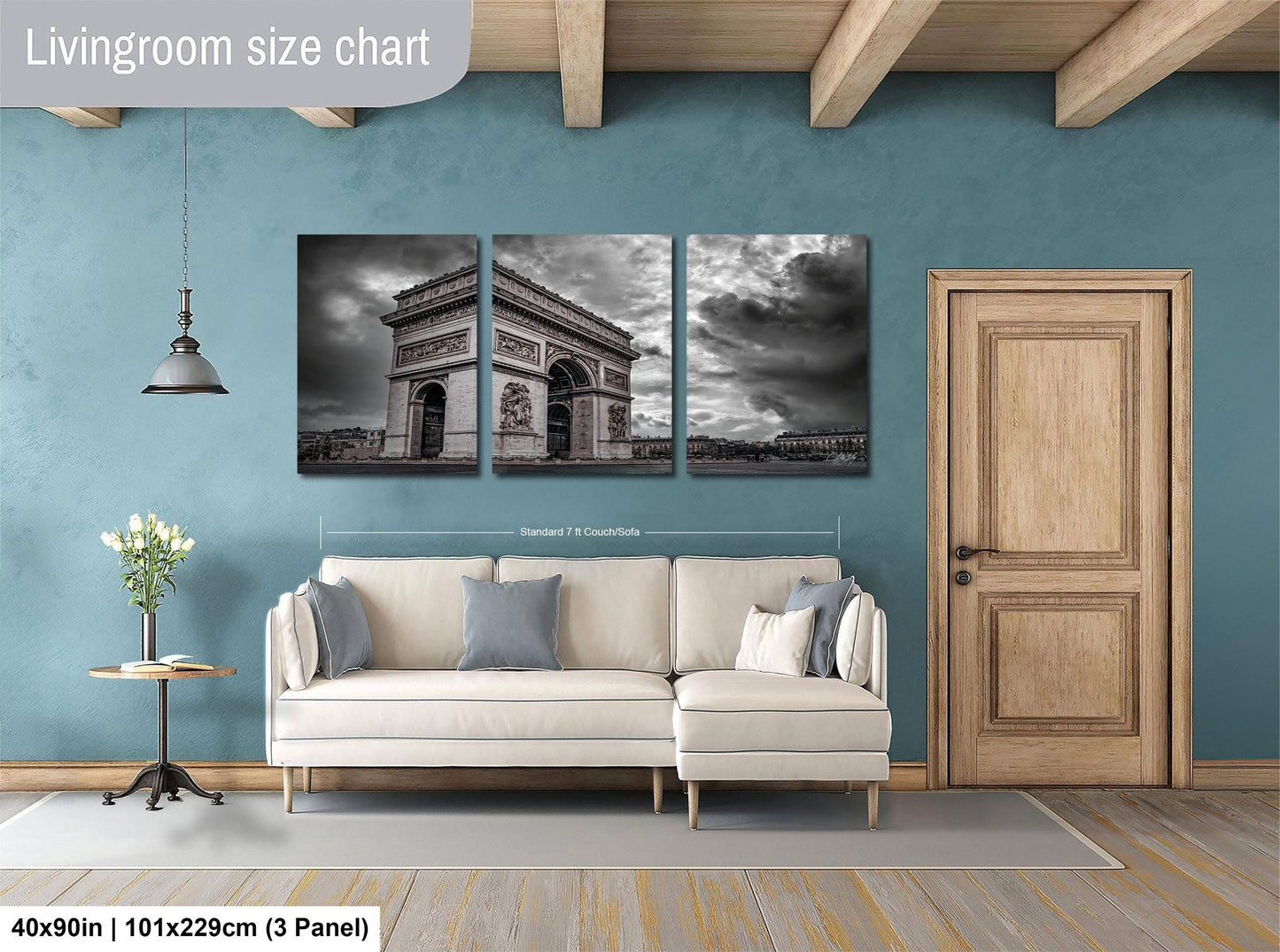 The image is a living room with a large wall art piece depicting the Arc de Triomphe in Paris. The wall art is divided into three panels, with the largest panel covering the entire wall. The living room has a white sofa and a wooden door, and the floor is covered with a gray rug.
