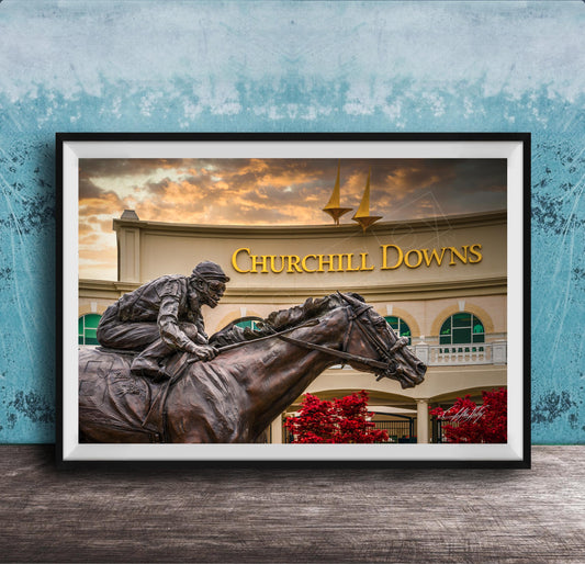 A bronze statue of a jockey riding a horse in front of a building with the sign " Churchill Downs" displayed.