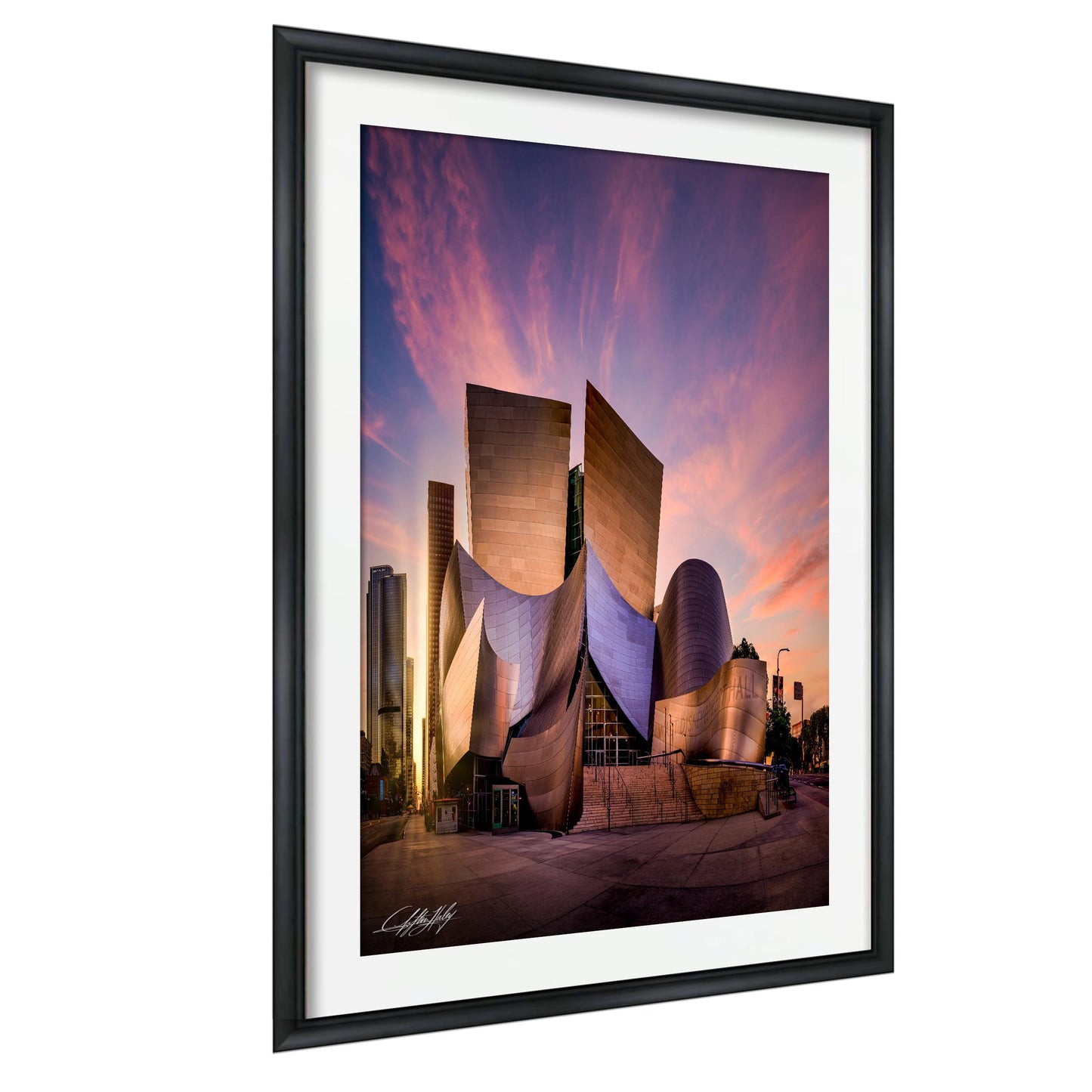 a modern, curved building with a unique architectural design, set against a vibrant sunset sky.