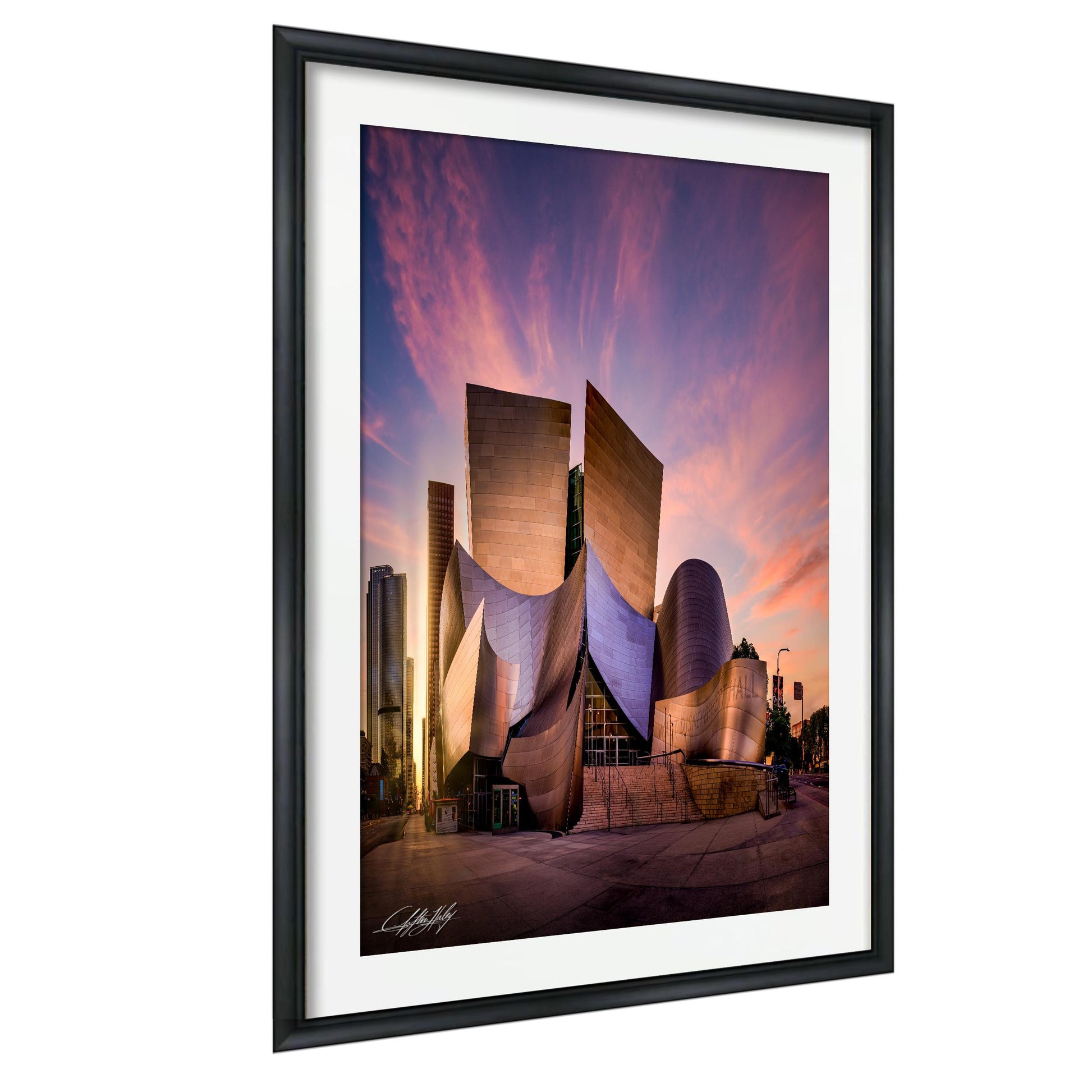 a modern, curved building with a unique architectural design, set against a vibrant sunset sky.