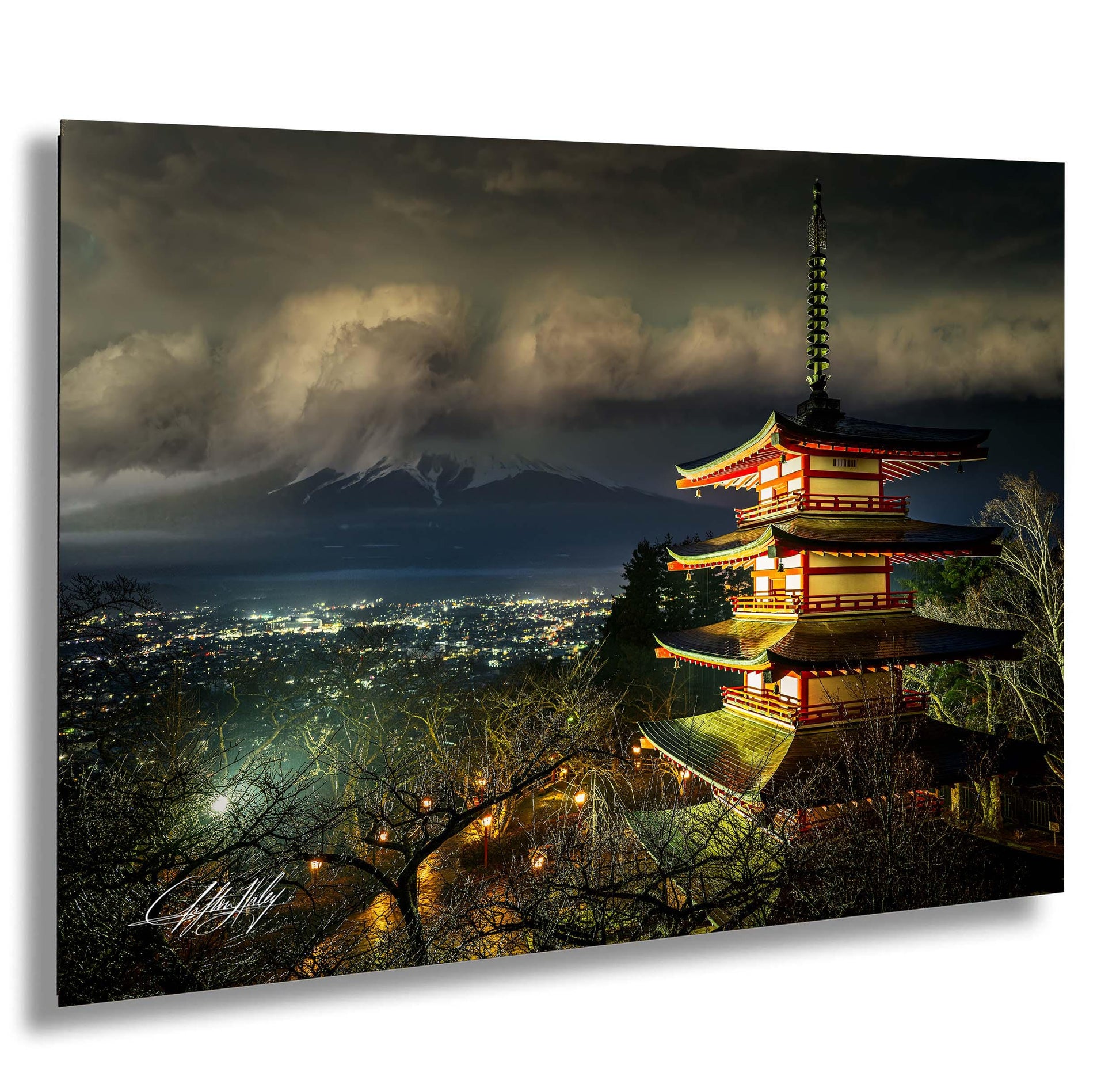 A multi-tiered pagoda-style building illuminated at night, with a mountainous landscape and a stormy sky in the background.