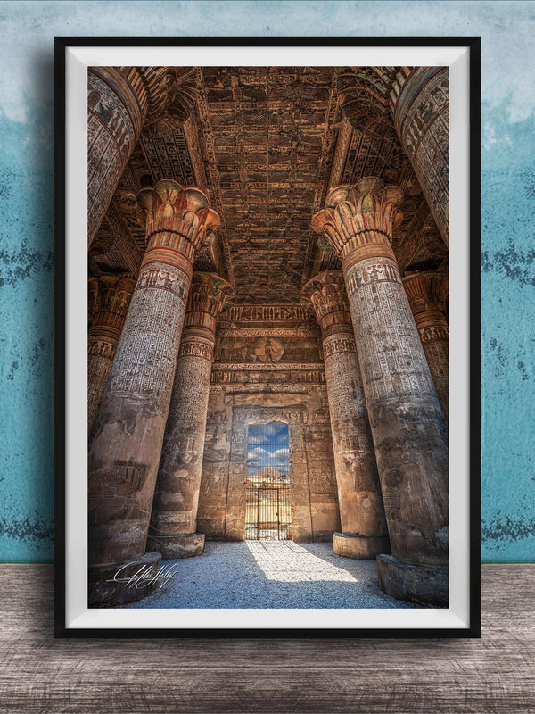 an ancient Egyptian temple with towering columns and intricate carvings, set against a blue wall with a textured pattern.