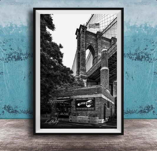 A black and white photograph of the Brooklyn Bridge, with the name 'LOOKS LOBSTER' displayed on the building.