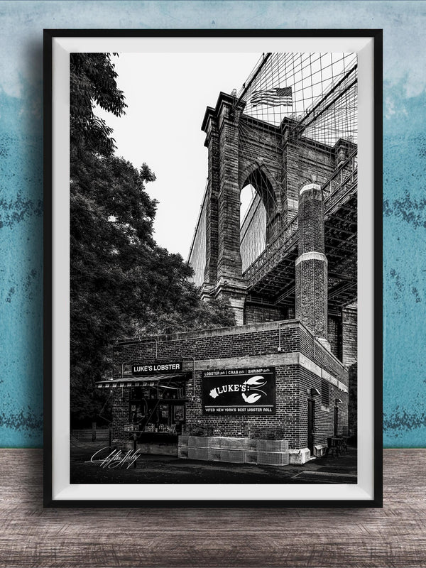 A black and white photograph of the Brooklyn Bridge, with the name 'LOOKS LOBSTER' displayed on the building.