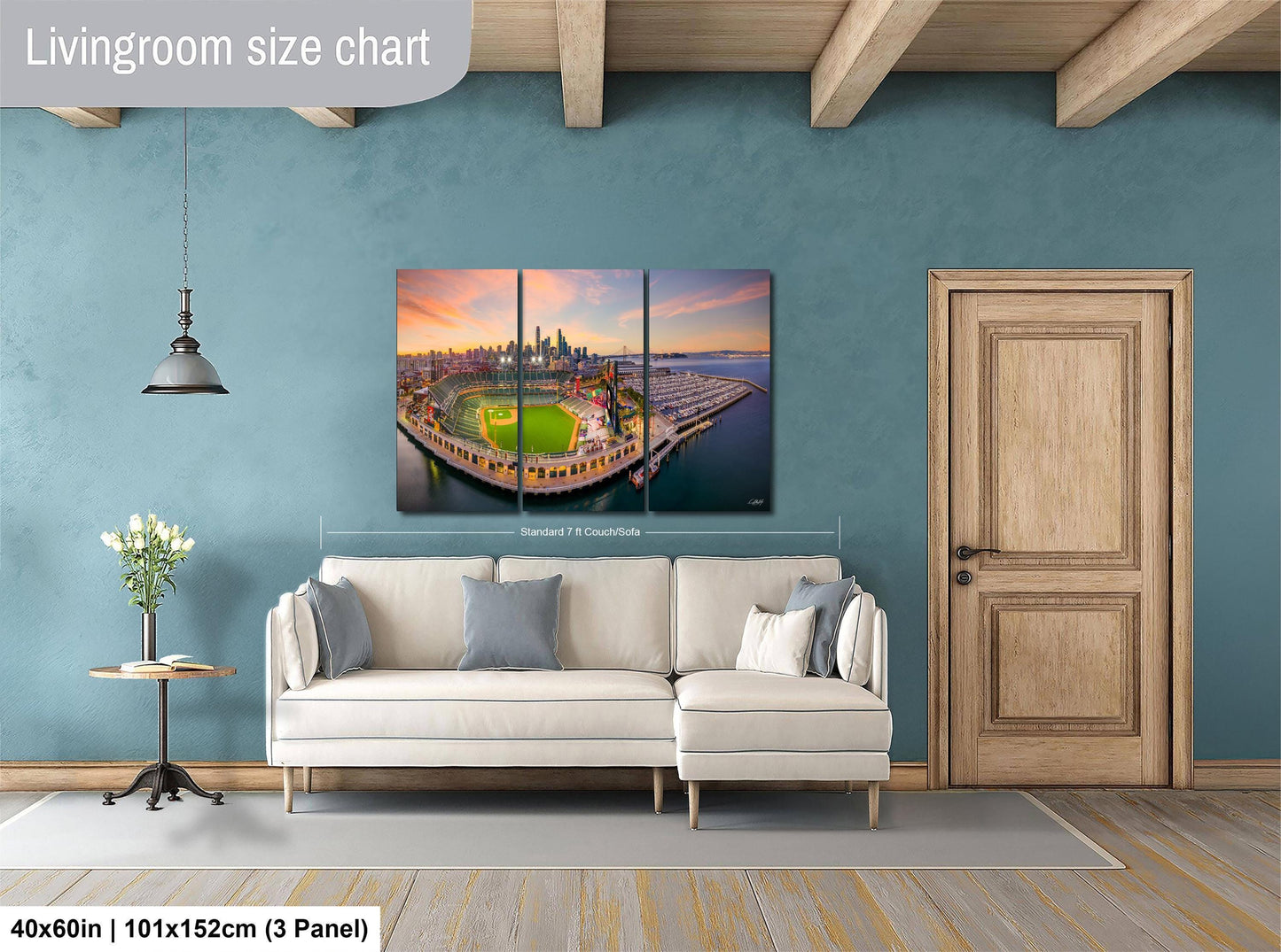 The image is a living room with a large, colorful, and detailed painting of a cityscape hanging on the wall. The painting is divided into three panels, and the living room has a white sofa, a wooden door, and a small table with a vase of flowers.