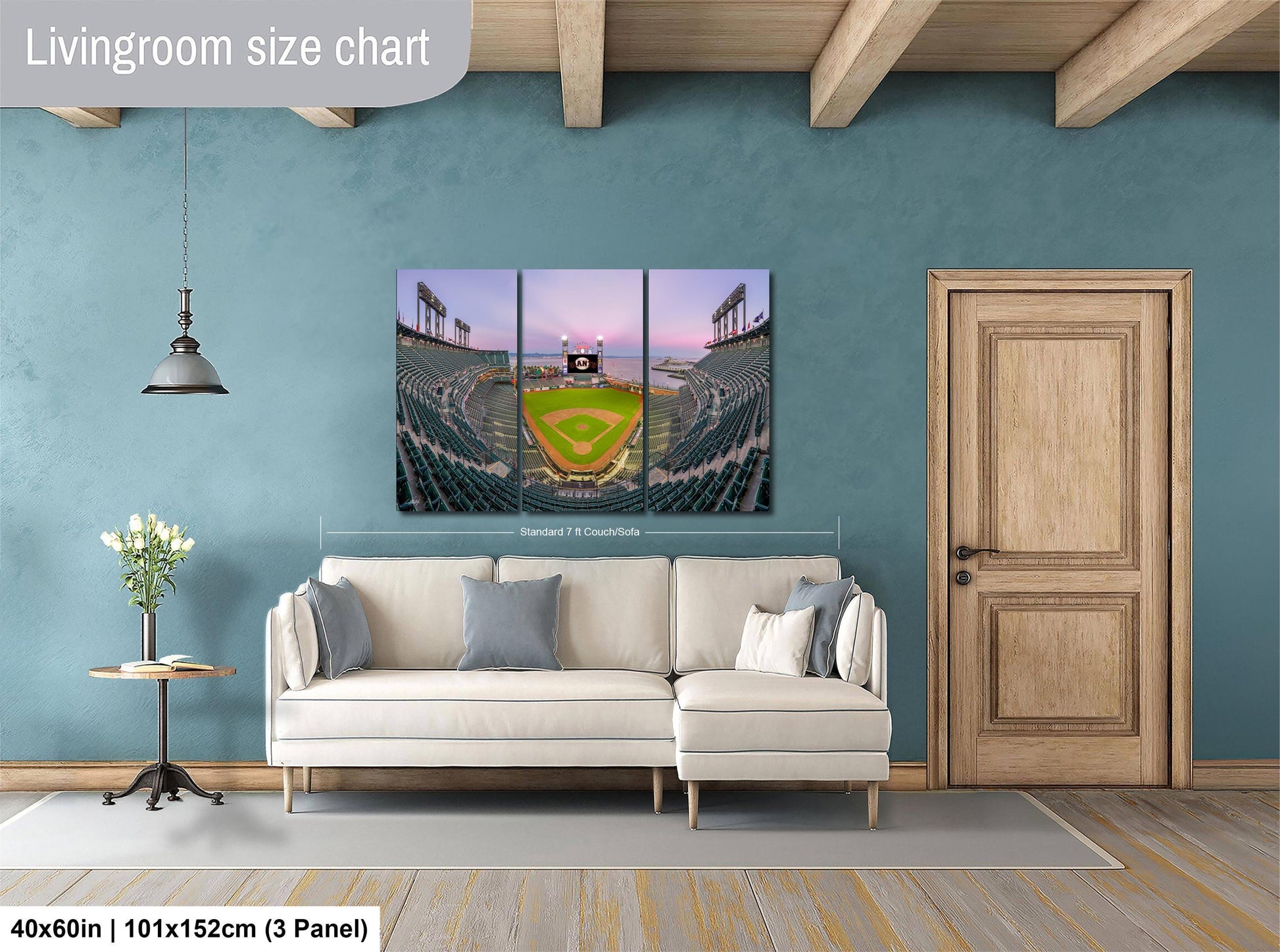 The image is a living room with a large wall-mounted painting depicting a baseball stadium. The painting is divided into three panels, with the top and bottom panels showing the stadium and the middle panel showing the field. The painting is framed by a wooden door and a white sofa, creating a cozy and inviting atmosphere.