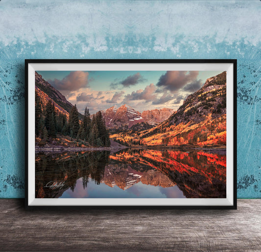 The image is a framed photograph depicting a scenic mountain landscape with a lake reflecting the mountains and trees.
