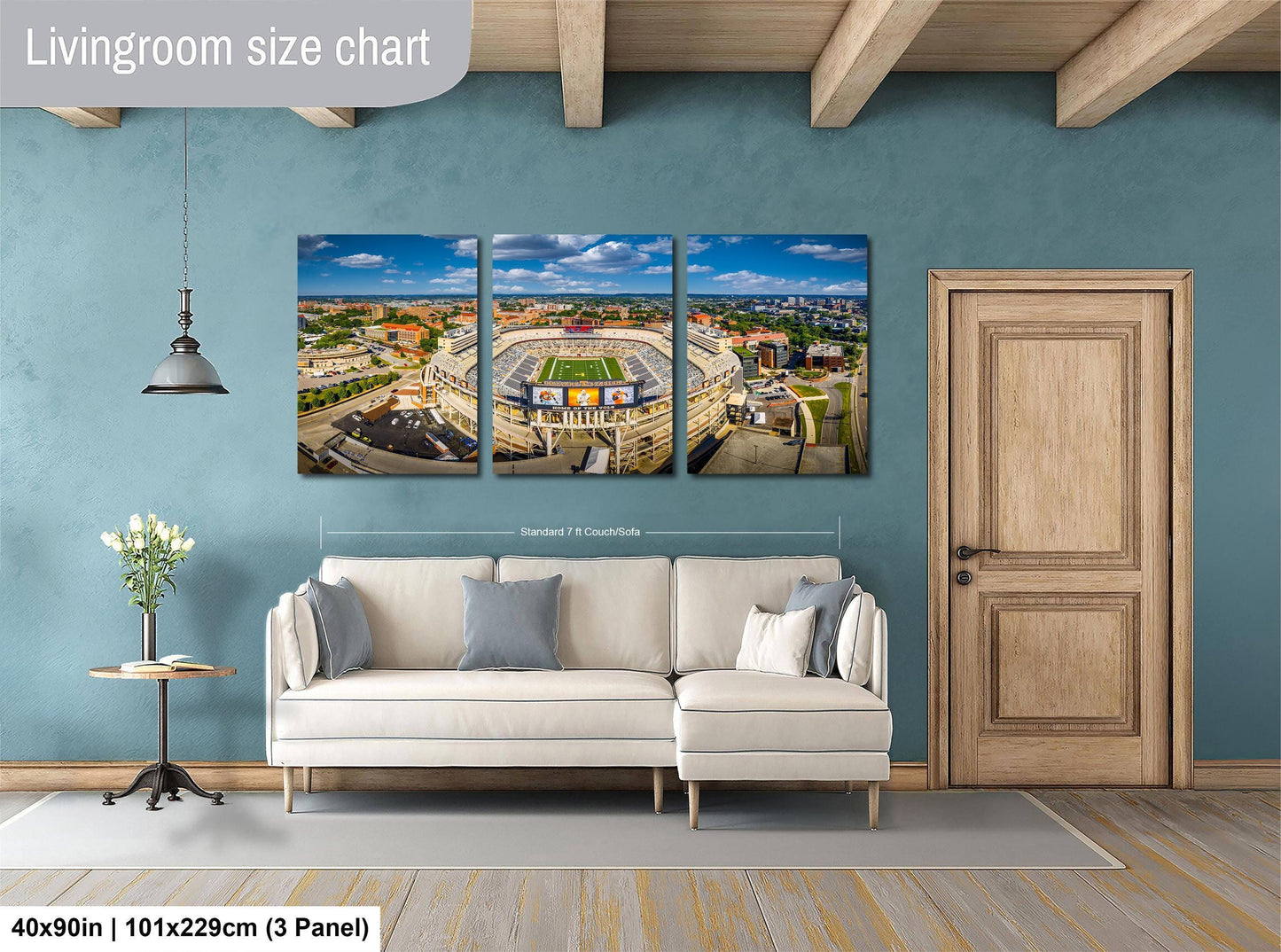 The image is a living room with a large wall-mounted painting depicting a cityscape, a white sofa, a wooden door, and a small table with a vase of flowers.