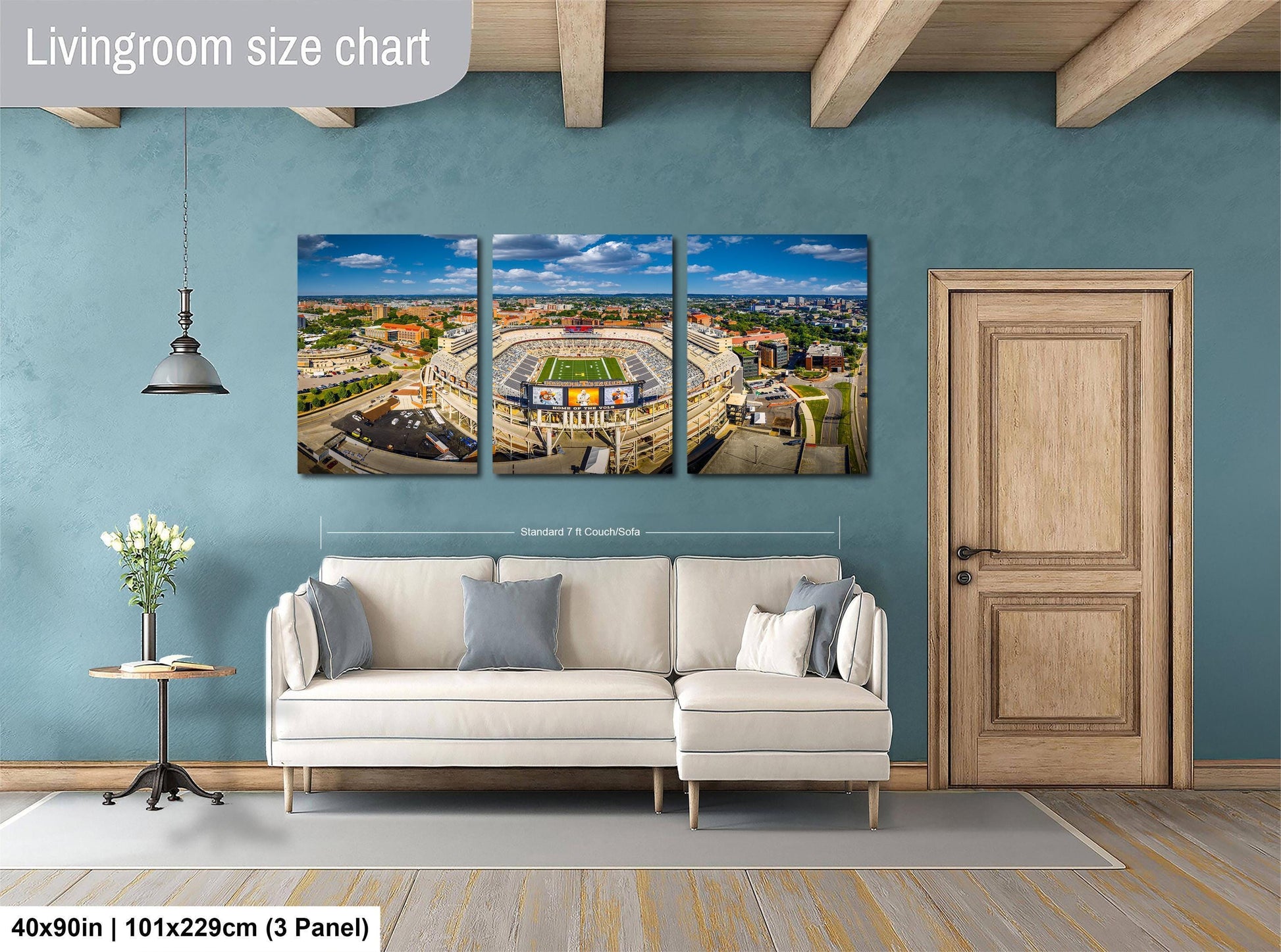 The image is a living room with a large wall-mounted painting depicting a cityscape, a white sofa, a wooden door, and a small table with a vase of flowers.