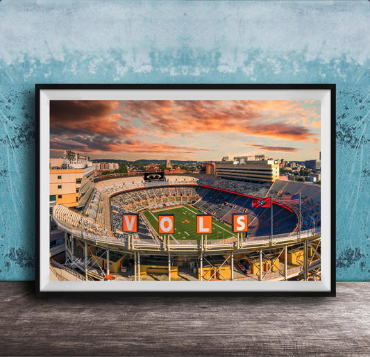 A framed photograph of a sports stadium with the word "VOLS" prominently displayed, set against a backdrop of a colorful sunset sky.