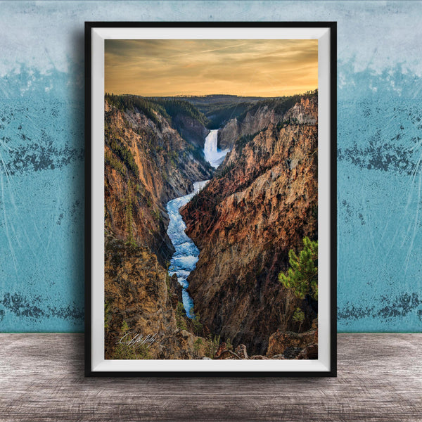 A framed photograph of a breathtaking waterfall cascading down a steep, rocky cliff face, with a vibrant sky in the background.