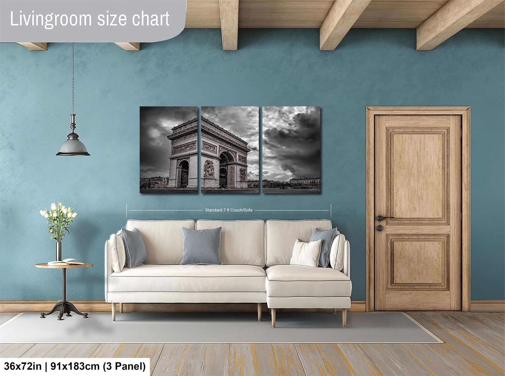 The image is a living room with a large wall art piece depicting the Arc de Triomphe in Paris. The wall art is divided into two panels, one above the other, and is mounted on a blue wall. The living room has a white sofa and a wooden door, creating a cozy and inviting atmosphere.