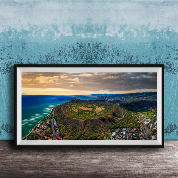 The image is a framed aerial view of a mountainous landscape with a coastal area, featuring a mix of green, brown, and blue colors.