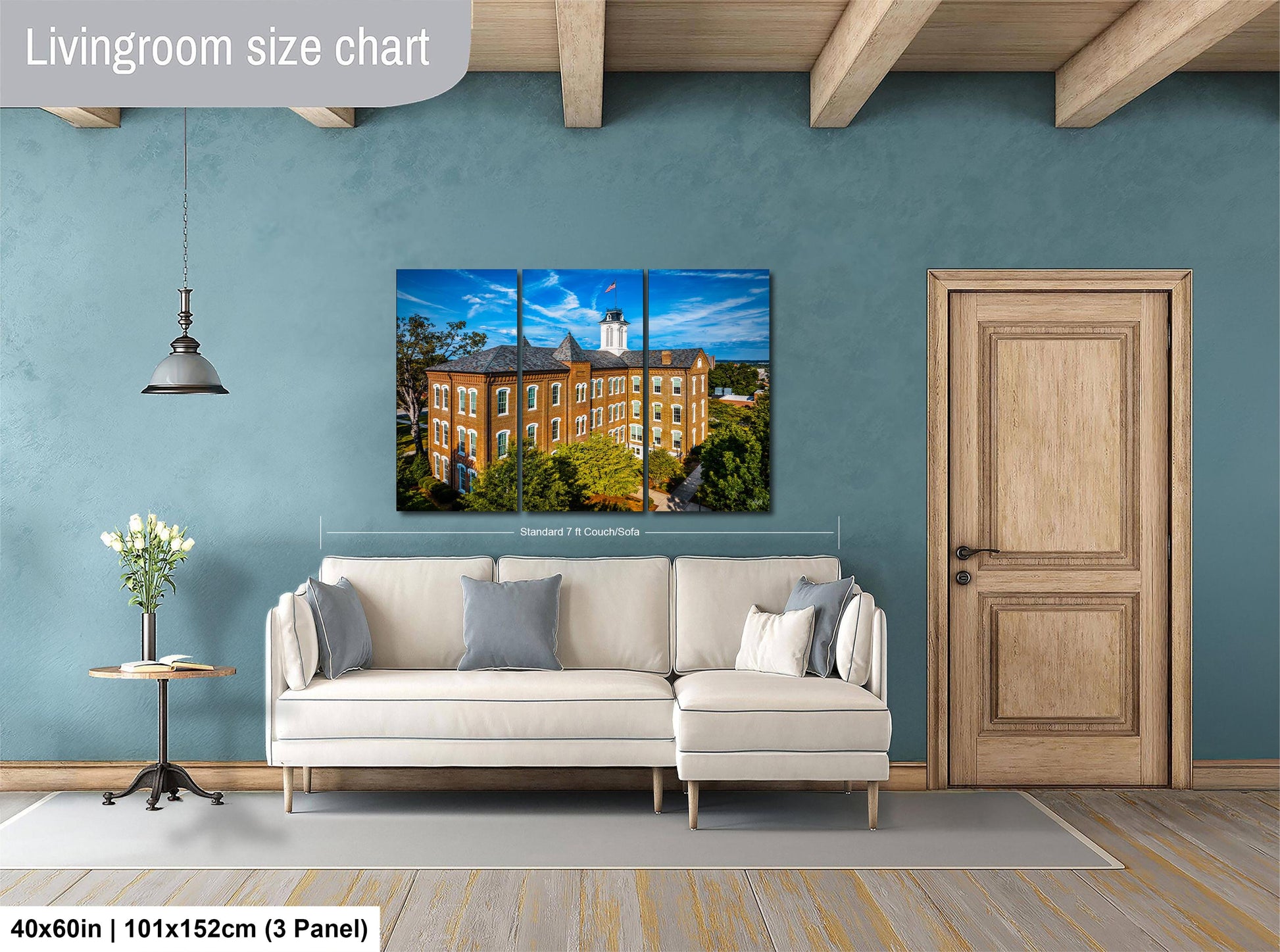 The image is a living room with a large white sofa, a wooden door, and a painting of a building on the wall.