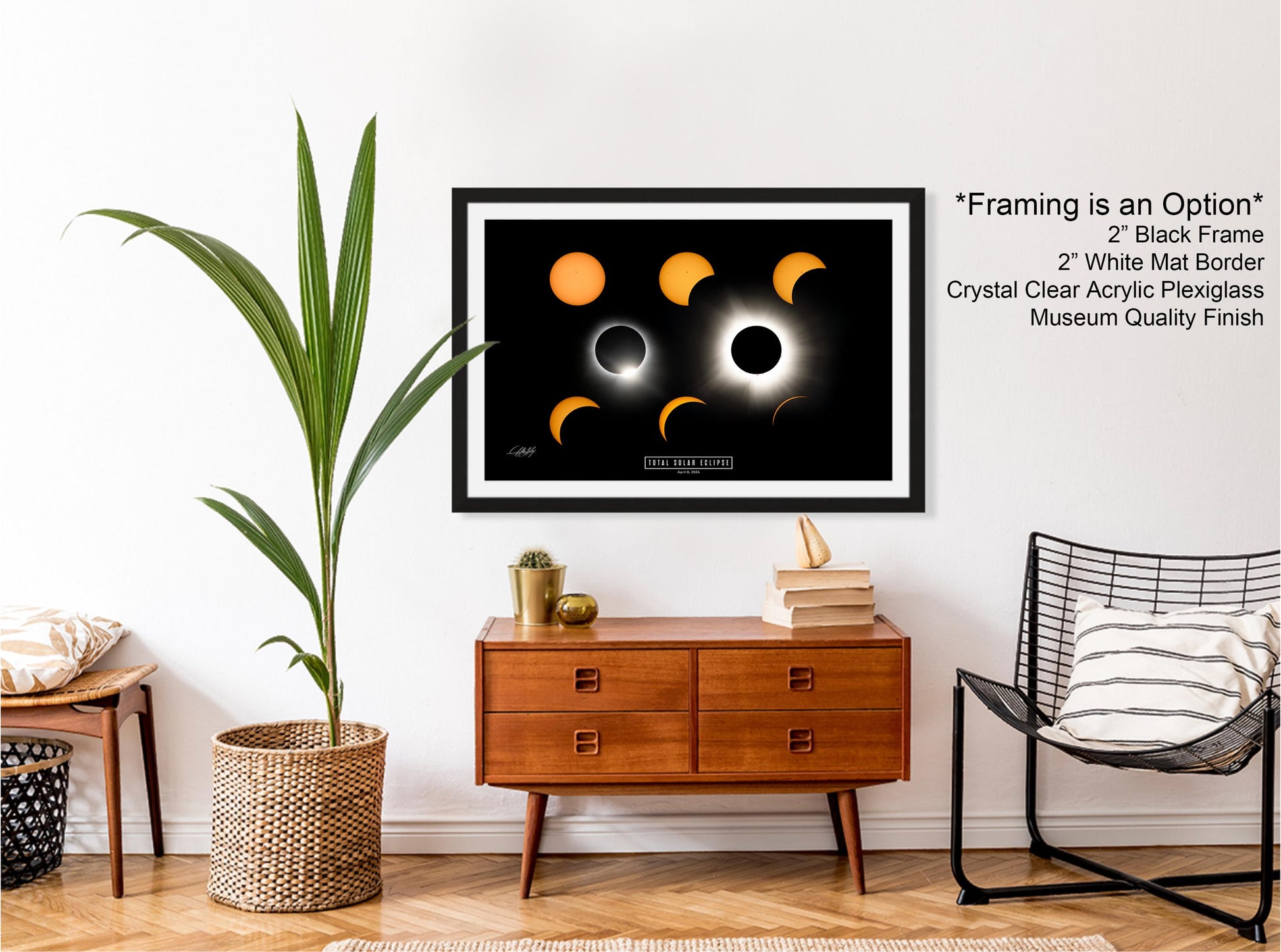 a framed poster of the solar eclipse, a potted plant, a wooden dresser, a black chair, and a stack of books, all arranged in a living room setting.
