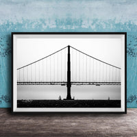 A black and white photograph of the Golden Gate Bridge in San Francisco, California, with a blue textured wall in the background.