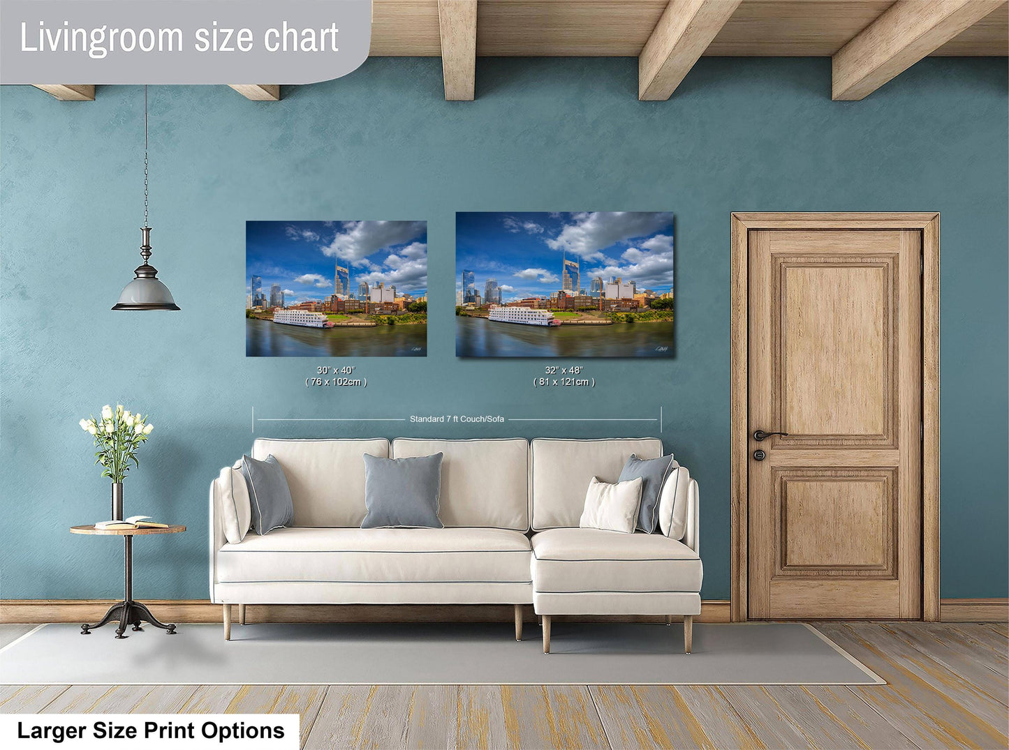 a living room with a white sofa and a wooden door. Above the sofa, there are two framed pictures of a cityscape, and the wall has a blue color. The living room appears to be well-lit and decorated.