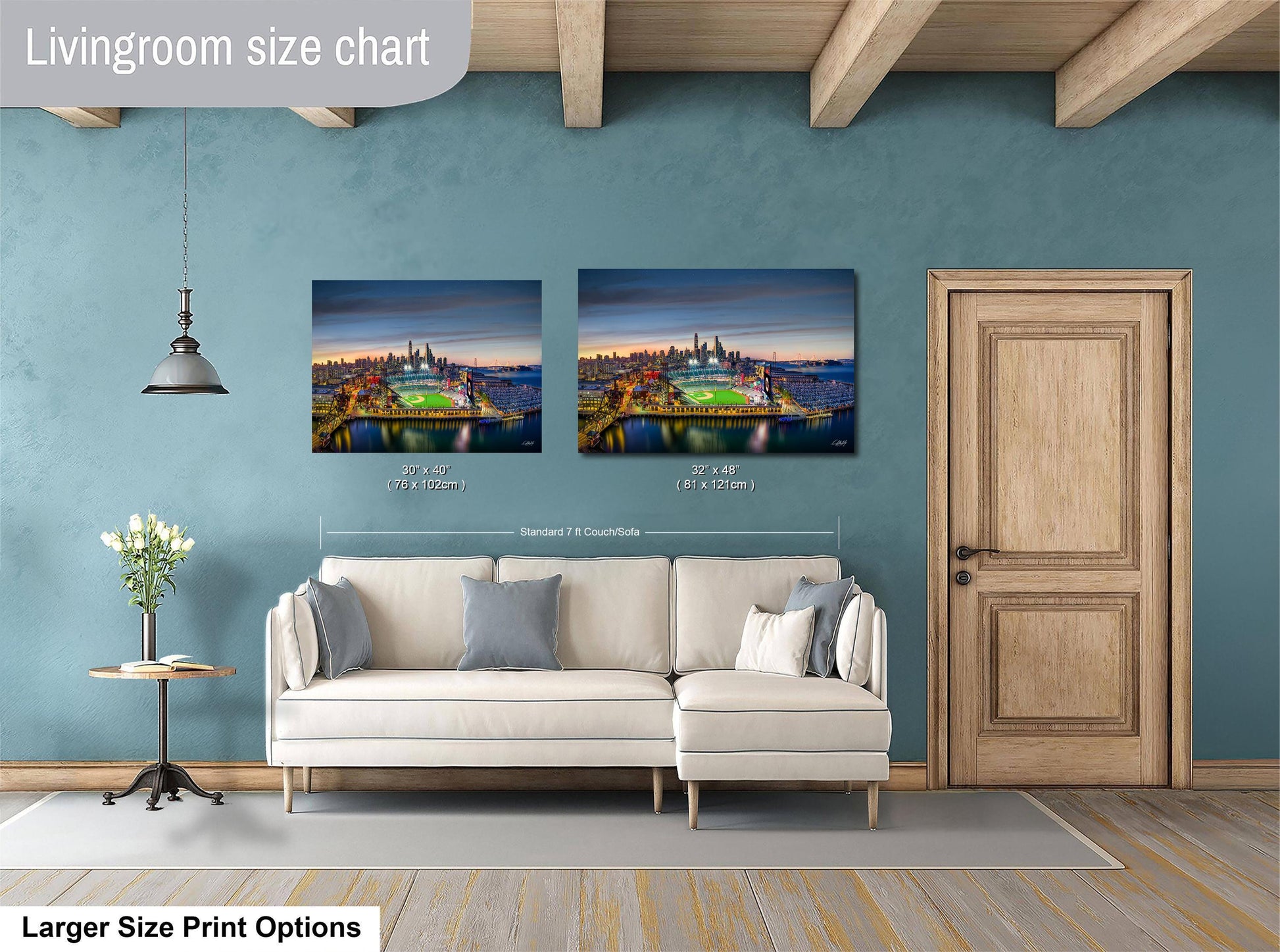 a living room with a white sofa and a wooden door. Above the sofa, there are two framed pictures of a city skyline at night, with one picture being larger than the other. The living room has a blue wall and a wooden ceiling.