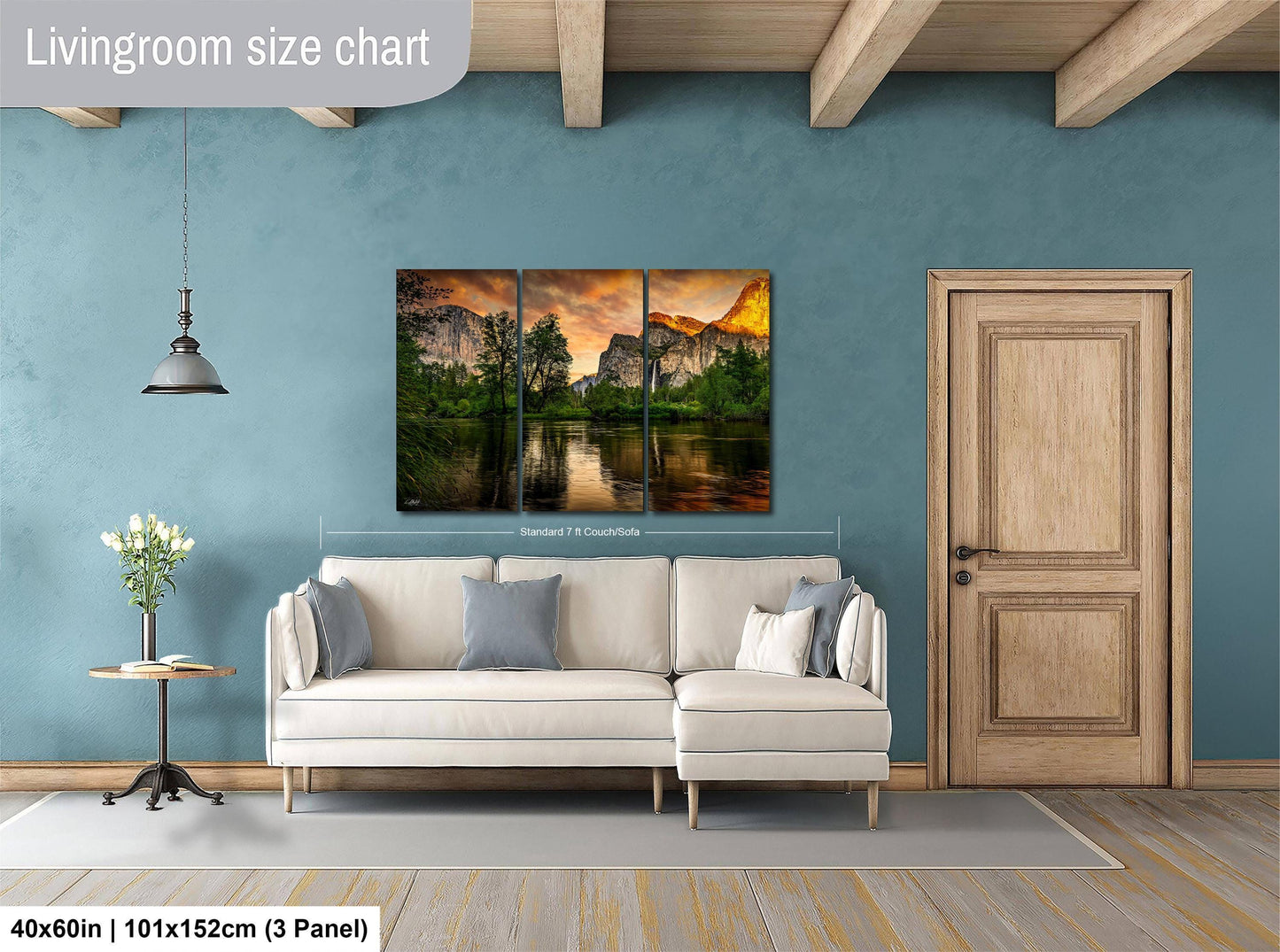 The image is a living room with a large, three-panel landscape painting hanging on the wall. The painting depicts a serene mountain scene with a lake and trees. The room has a white sofa and a wooden door, creating a cozy and inviting atmosphere.