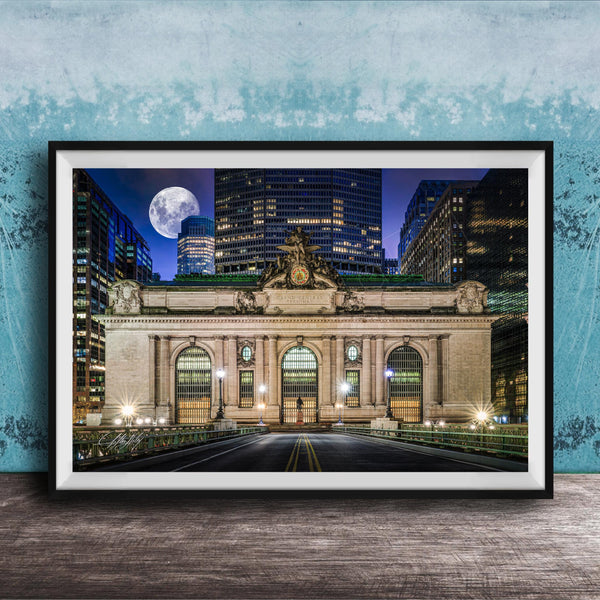 A framed photograph of the Grand Central Terminal in New York City at night, with the iconic building illuminated and a full moon visible in the sky.