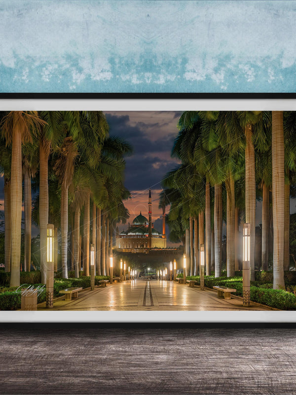 A framed photograph depicting a serene nighttime scene of a palm-lined walkway leading to a building, with the sky illuminated by the warm glow of the setting sun.