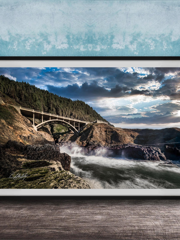 a scenic view of a bridge spanning over a rushing river, with a dramatic sky and lush green trees in the background.