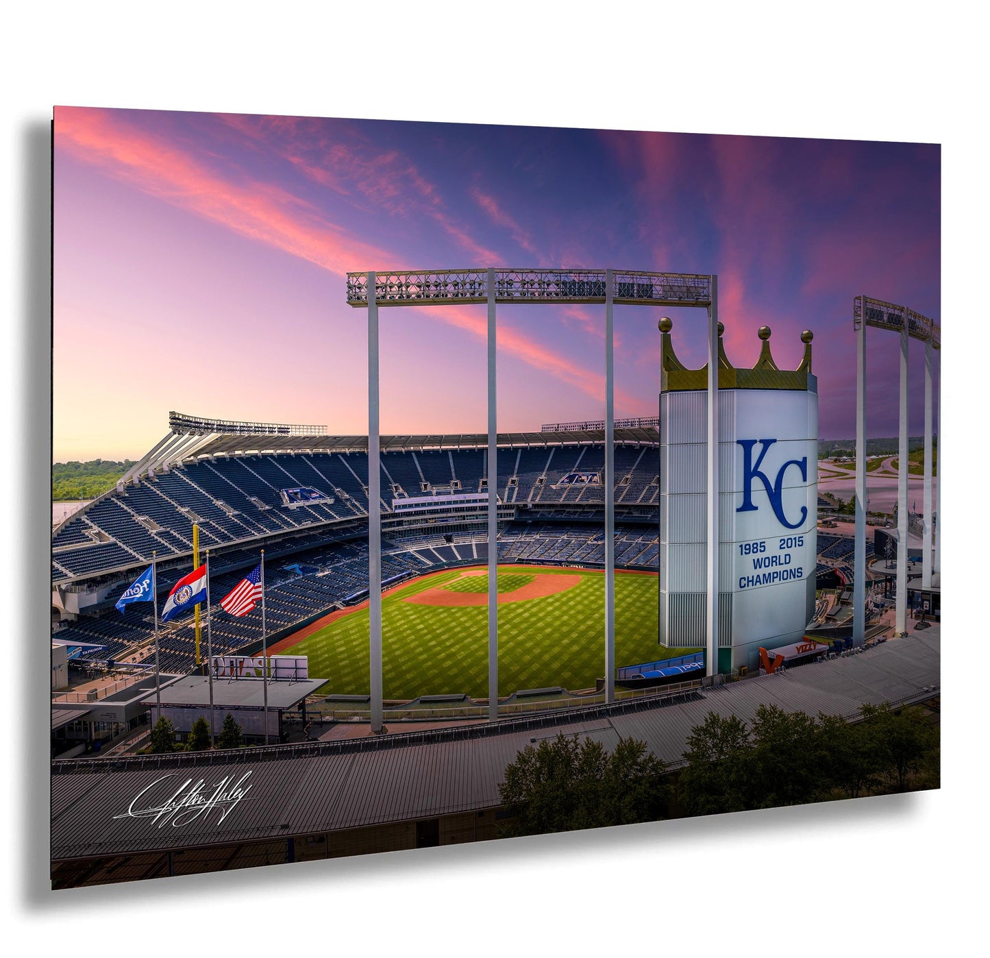 A panoramic view of a baseball stadium at sunset, with the Kansas City Royals logo prominently displayed on the field.