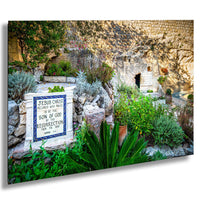 a sign with religious text, surrounded by a lush garden with various plants and shrubs.
